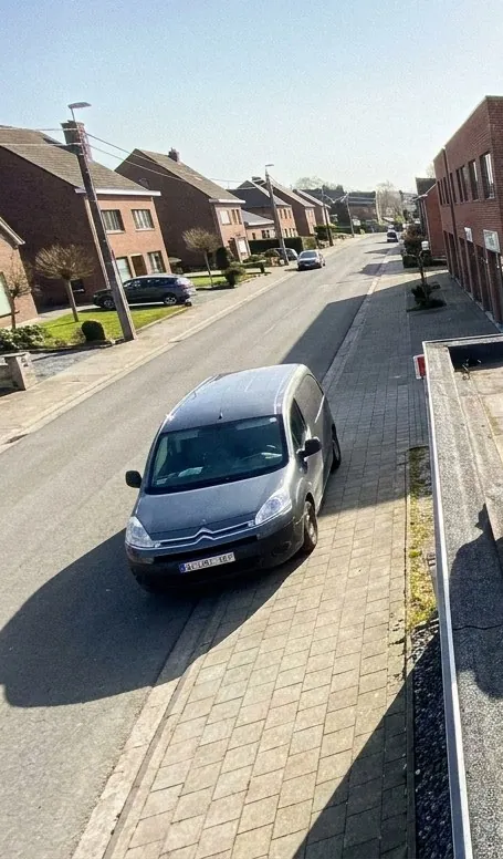 Rue résidentielle de Wavre vue depuis un toit plat en chantier de Wavre Roofing, maisons en briques et immeuble de bureaux